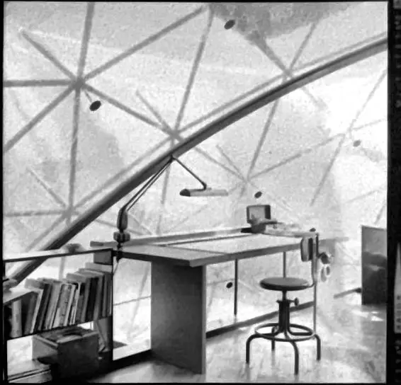 A drafting table, stool and bookshelf under the skin.