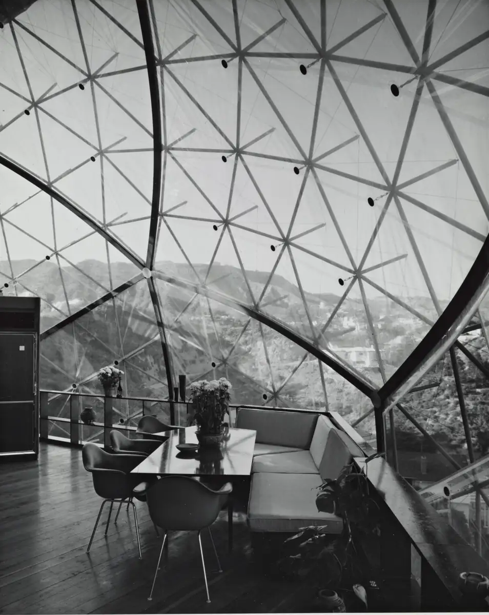 Inside the dome: a dining table under the triangulated frame, the canyon beyond the glazing