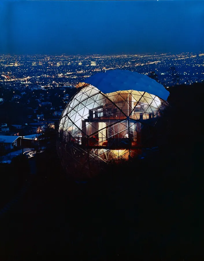 The dome lit from within at twilight above the lights of Los Angeles